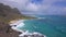 View of Makapuu beach. Waves of Pacific Ocean wash over yellow sand of tropical beach. Magnificent mountains of Hawaiian