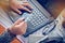 View of male hands holding credit card numbers typed on the computer keyboard while sitting at a desk - focus hand