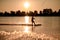 view of male wakeboarder riding water against bright sunset background