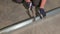 View of male worker hammering dowel nails in metal rail.