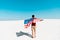 View of man with american flag on windy sandy beach against clear blue sky