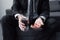 View of man in black suit holding glass of water and handful of pills