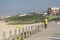 View of man looking to the beach on pedestrian wooden walkway, buildings and