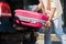 View of man putting pink luggage in car trunk