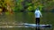 view of man on supboard in the middle of autumn lake