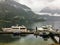 A view of a marina full of boats on a rainy grey day in at the end of remote, secluded inlet surrounded by forests and mountains.