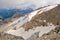 View from Marmolada summit. Sharp rocks with glacier, green meadows in the background. Clouds. Dolomites.