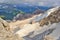 View from Marmolada summit. Sharp rocks with glacier, green meadows in the background. Clouds. Dolomites.