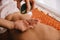 View of masseur pouring fragrance oil on hand and woman lying on massage mat