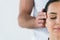 View of masseur putting hands on temples of woman isolated on white