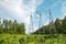 View of the masts of the power line against the background of blue sky, white clouds, beautiful green forest in the rays