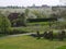 View with meadow, trees and path ,flowering cherry trees plantation, trees tied to poles, village in strong blurred background