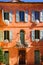 View on mediterranean bright facade of red ochre house with blue window shutters, green doors, flower pots - Roussillon en
