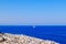 View on the Mediterranean Sea with rocks in the front and a sailboat in the back