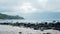 The view on Menganti Beach, Kebumen, Central Java, Indonesia with white sand, rocks, waves, and a backdrop of towering hills