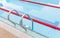 The view of metallic ladder of swimming pool with marked lanes.