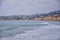 View from Mission Beach in San Diego, of Piers, Jetty and sand, around surfers, including warning signs, palm trees, waves, rocks,