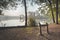 View of misty lake with trees reflected in the water and post in foreground