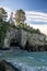 View into Monkey bay, rocky cove with trees with crystal clear blue water. New Zealand