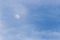 View of moon through some clouds in the blue sky