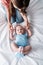 View of mother in denim jeans sitting near adorable infant in blue baby bodysuit