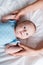 View of mother holding hands of adorable infant in blue baby bodysuit