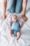 View of mother in jeans sitting near happy infant in blue baby bodysuit