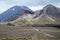 View of Mount Ngauruhoe - Mount Doom from Tongariro Alpine Crossing hike with clouds above and red crater in foreground