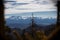 View from the mountain peak to the great snow-capped mountain peaks. Beautiful blue sky and green forest with one disturbing tree