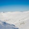 View of mountain peaks and rocks covered with snow around the clouds under the blue sky