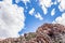 View of a Mountain range with large red rocky outcrops covered with lush green vegetation, Montagu Springs