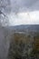 View of the mountain valley through the water jets of the waterfall