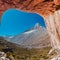 the view of the mountains through the arch in a rock formation