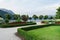 View of the mountains, the lake and the embankment of the city with trimmed trees, shrubs, lawn and flower beds