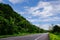 View of mountains, sky, streams among green forests.