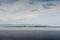 View on Mutton island from the ocean. Old Lighthouse and water sewage plant. Cloudy sky and blue water