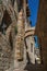View of narrow alley with old buildings, arch and woman walking in San Gimignano.