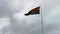 View of the national flag of the Republic of Angola isolated against a sky with clouds, fluttering in the wind, a symbol of