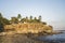 View of natural rocky beach and cliff with palm trees in El Tunco, El Salvador. Stones and rocks on the beach at sunset or sunrise