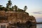 View of natural rocky beach and cliff with palm trees in El Tunco, El Salvador. Stones and rocks on the beach at sunset or sunrise