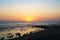 View of natural rocky beach and cliff with palm trees in El Tunco, El Salvador. Stones and rocks on the beach at sunset or sunrise