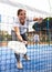 View through net of young female paddle tennis player