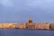 View of the Neva embankment from the river, buildings, the dome of St. Isaac`s Cathedral, at sunset in the sun, birds in the sky