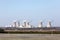 View of a nuclear power plant. View of smoking chimneys of nuclear power plant, power lines and forest, under blue sky with white