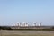 View of a nuclear power plant. View of smoking chimneys of nuclear power plant, power lines and forest, under blue sky with white