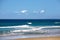 View of the ocean with wild waves and a surfer walking towards the shore of Cape Byron in Australia