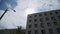 View ofgray concrete panel building above there is blue sky with white clouds