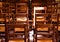 View on  old brown wood chairs with backrest in a row inside catholic empty church illuminated by natural sun light