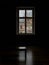 View of old buildings with rusty roofs from a dark room with a bench and parquet floor.