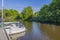 View of old man in parked motor boat.  Beautiful green trees on coast on blue sky background. Sweden. Europe.